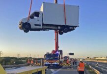 Unfall auf der A99: Feuerwehrkran hebt Kleinlaster auf Abschlepper